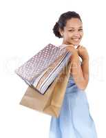 Shopping is her special treat. Young woman smiling while holding her purchases after a shopping day - isolated.
