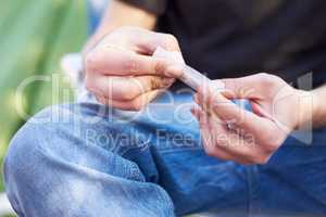 Everything has a gateway. Shot of a unrecognizable person rolling a large marijuana joint.