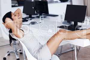 Relax after a hard day at the office. Happy mixed race businesswoman relaxing with her feet up on desk.