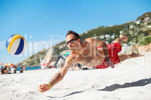 Diving for glory. Shot of a beach volleyball game on a sunny day.