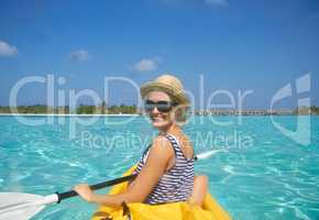 Paddling towards the beach. A beautiful young woman paddling on a boat in a tropical ocean.