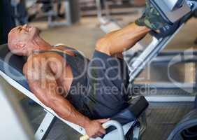 Feeling determined. Shot of a male bodybuilder doing leg exercises on a machine at the gym.