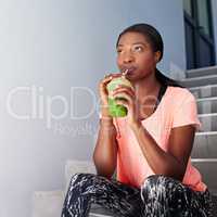 Thoughts of fitness. Shot of an attractive young woman drinking juice while exercising outdoors.