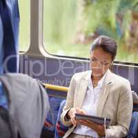 Shes never bored on the bus. Shot of a businesswoman using a digital tablet while commuting on a bus.