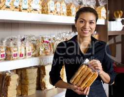 This is yummy stuff. Portrait of an attractive woman holding some of the baked goods she sells at her bakery.