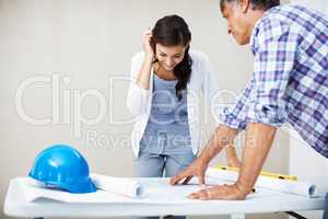 Happy woman discussing with architect over blueprint. Happy young woman smiling while discussing home renovation plans with architect over blueprint.