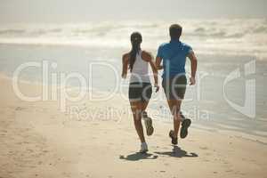 There are no shortcuts to any place worth going. Rearview shot of a young couple jogging together on the beach.
