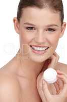She uses a moisturizer that matches her skin type. Close-up shot of a pretty teenage girl holding a tub of moisturizer.