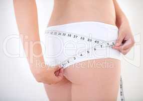 The results are there for all to see. Cropped image of a young woman measuring her buttocks with a measuring tape.