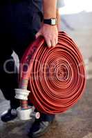 Coiled and ready for action. Closeup shot of a fireman carrying a coiled fire hose.