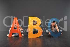 Where literacy starts. Studio portrait of a diverse group of kids holding up letters of the alphabet against a gray background.