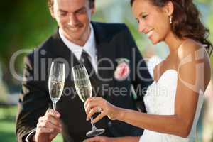 Heres to our romance. Cropped view of a young bride and groom standing together and toasting their marriage.