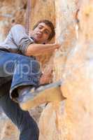 Cliff climber. Portrait of a young rock climber on a climbing rockface.