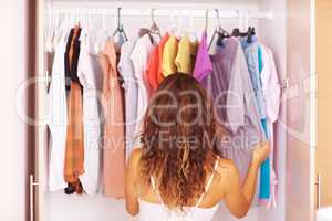 Woman going through her clothes. Rear view of a woman going through the clothes in her closet.