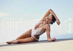 Addicted to summer. Shot of a beautiful young woman in a swimming costume sunbathing next to a pool.