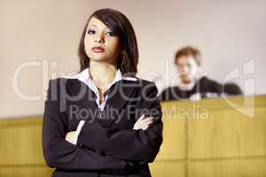 Well-qualified to win in court. Stern young advocate standing in the courtroom with her arms folded.