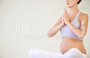 Keeping her mind and body in good shape for the baby. A young pregnant woman sitting in a yoga pose - cropped.