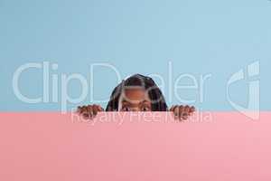 Say what. Studio portrait of a young boy peering from behind a blank signboard.