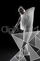 Geometric goddess. Studio shot of a woman wrapped in fabric and surrounded by geometric shapes against a black background.