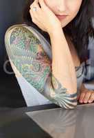 The beauty is in the detail. Cropped shot of a young tattoo artist showing off her half-sleeve tattoo.