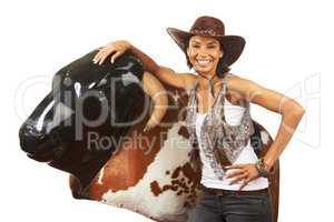 Not afraid to take on the bull. Studio shot of a beautiful young cowgirl standing next to a mechanical bull against a white background.
