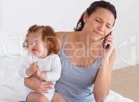 Trying to balance it all - Motherhood. A mother trying to have a phone conversation while her baby is crying in the background.