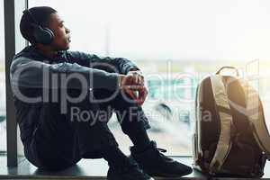Patiently waiting for departure. Shot of a young man listening to music while sitting at the airport waiting for departure.