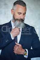 Looking sharp and confident. Studio shot of a handsome middle aged businessman wearing a formal suit while standing against a grey background.