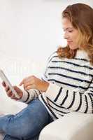 Adding a new entry to her microblog. Shot of a young woman using her digital tablet at home.