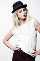 Im whats hip. A trendy young blonde model wearing a bowler hat while isolated on white.
