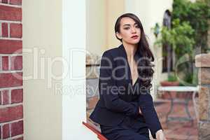 Urban chic. Shot of a woman wearing a classic feminine suit leaning against an architectural feature.