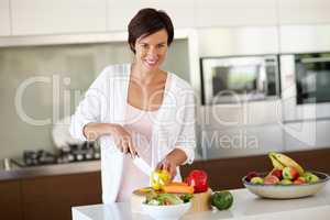Creating a delicious dish from scratch. Portrait of an attractive woman chopping vegetables at the kitchen counter.