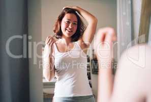 I have to say I look pretty good with this hair style. Cropped shot of an attractive young woman admiring her hair while standing in front of the mirror in her bedroom at home.