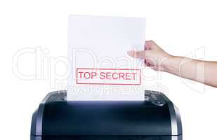 Getting rid of top secret information. Studio shot of a womans hand placing a confidential document into a shredder against a white background.