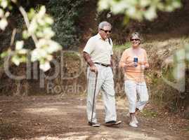 Stretching their legs on a leisurely stroll. A senior couple out for a walk in the forest together.