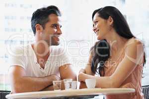 Blissfully happy in the bistro. Shot of a young couple grabbing a cup of coffee together.
