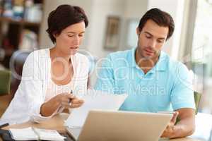 Reviewing their home finances. Shot of a couple sitting with a laptop busy doing budget calculations.