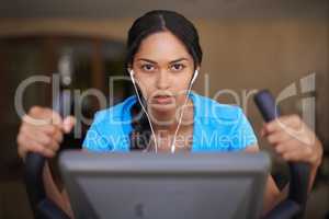 Full body workout. Shot of a young ethnic woman working out in the gym on a stationary bike.
