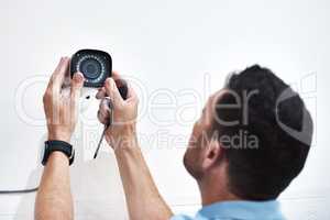 Can you guys see me down there. Shot of a mature man installing a security camera on a building.