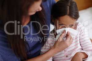 When a cold strikes.... Shot of a mother helping her sick daughter to blow her nose.