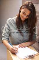 Online shopping makes buying gifts SO easy. A beautiful young woman signing for a package outside her home.