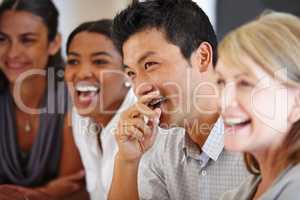 Sharing the joke. Shot of an Asian man laughing at a table with his coworkers out of focus.