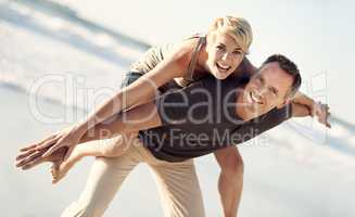 Forever playful. A husband giving his wife a piggyback ride on the beach.