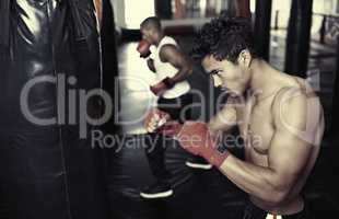 Hes dedicated to the sport of boxing. Shot of a young male boxers training on heavy bags.