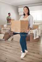 Home ownership is a feeling that makes lifes daily grind worth facing. Shot of a woman holding a box while moving into her new home with her partner.