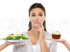 Should I or not. Studio shot of a young woman choosing between a healthy and unhealthy diet.