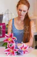 An eye for form and beauty. Beautiful young woman arranging lillies into a floral bouquet.