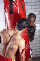 Training to remain undefeated. Two boxers practicing on a punching bag together.