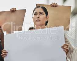 Shes ready to fight. Low angle shot of an attractive young woman holding a sign while taking part in a political rally.