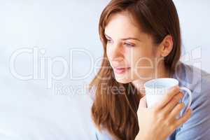 Young Caucasian female having a thought over coffee. Portrait of a cute young woman lost in deep thoughts with a coffee cup.
